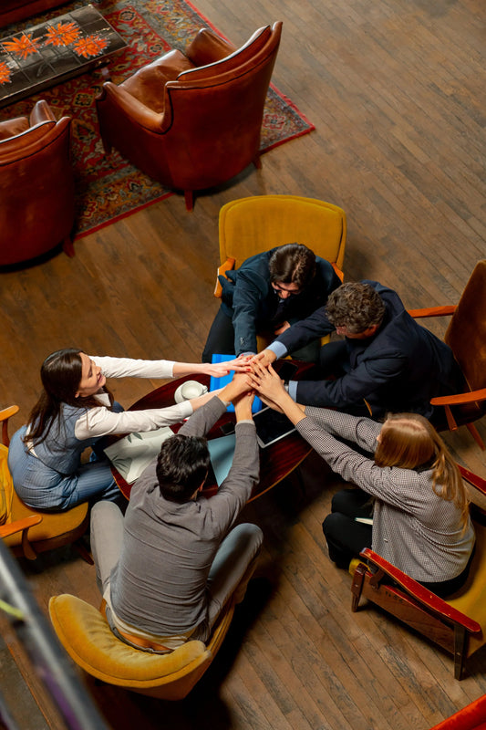 Zakelijke teamleden in stijlvolle kantoorruimte doen handen samen voor teamwork